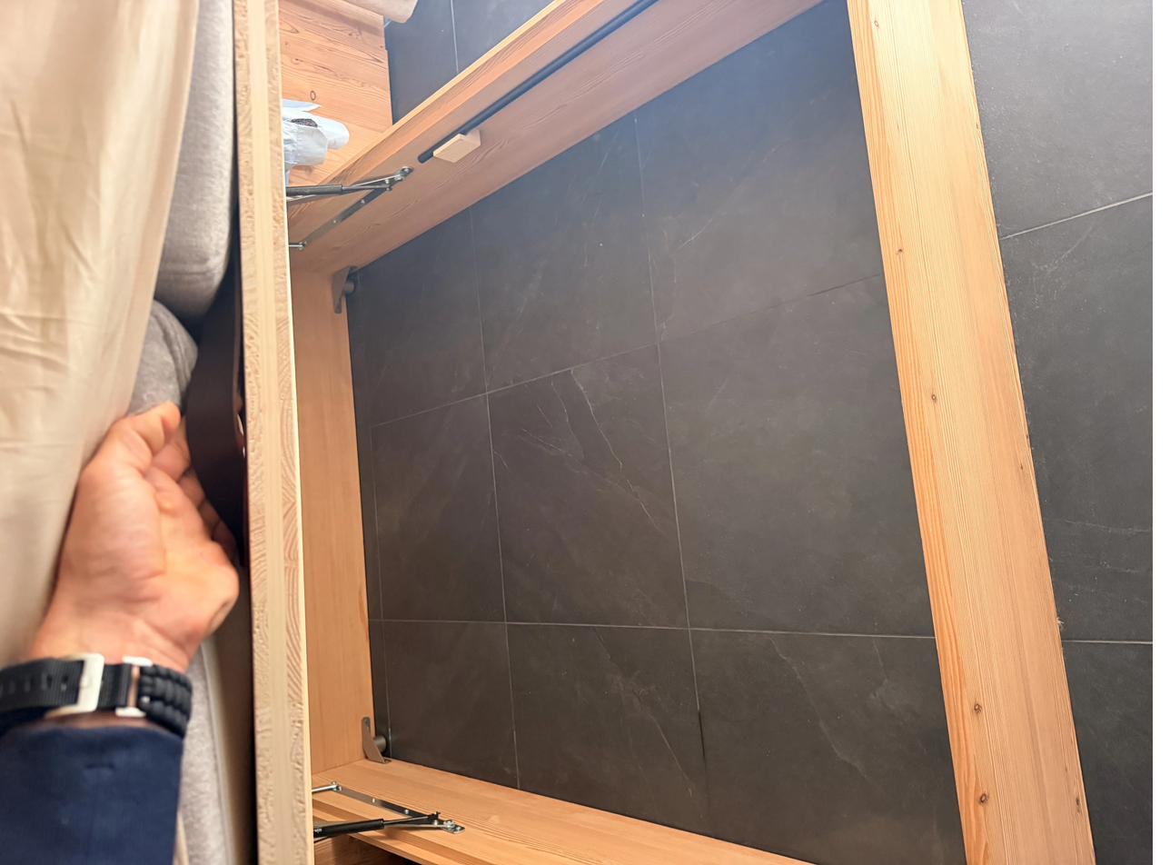 Lifting the Nest bed by the leather handle to access suitcase storage